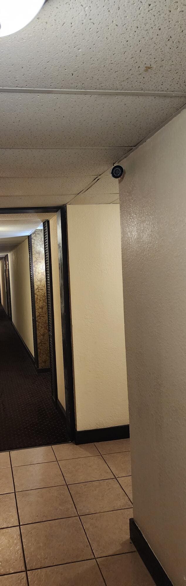 hallway with a drop ceiling and light tile patterned floors