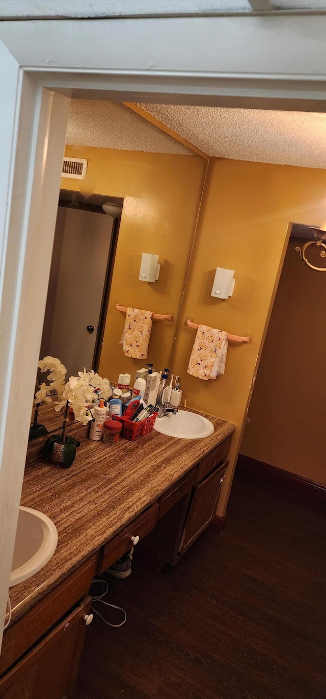 bathroom with a textured ceiling, hardwood / wood-style floors, and vanity