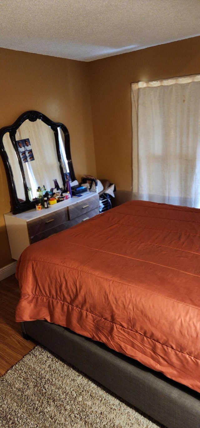 bedroom with a textured ceiling and dark wood-type flooring