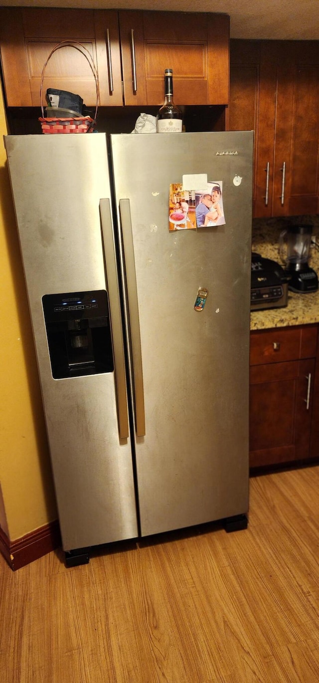 room details with stainless steel fridge with ice dispenser and light hardwood / wood-style floors