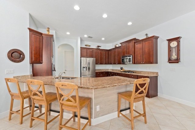 kitchen featuring a kitchen breakfast bar, light tile patterned floors, sink, kitchen peninsula, and stainless steel appliances