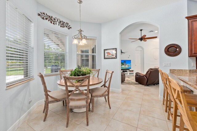 tiled dining area with a wealth of natural light and ceiling fan with notable chandelier