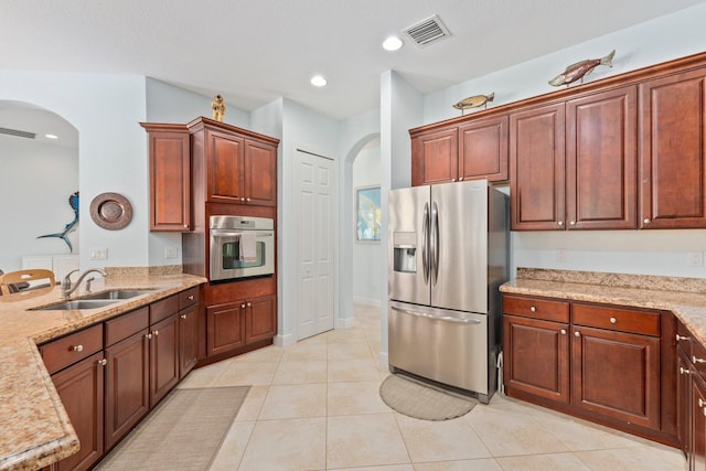 kitchen featuring appliances with stainless steel finishes, light stone counters, light tile patterned floors, and sink