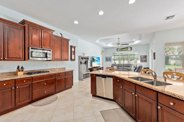 kitchen featuring sink, light tile patterned floors, ceiling fan, a raised ceiling, and stainless steel appliances