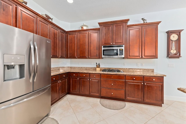 kitchen with stainless steel appliances, light tile patterned floors, and light stone counters