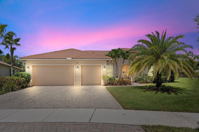 mediterranean / spanish-style house featuring a garage and a yard