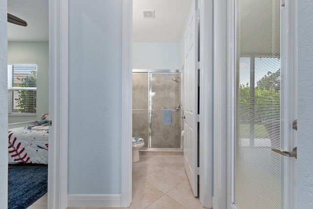 bathroom featuring a shower with shower door, toilet, and tile patterned flooring