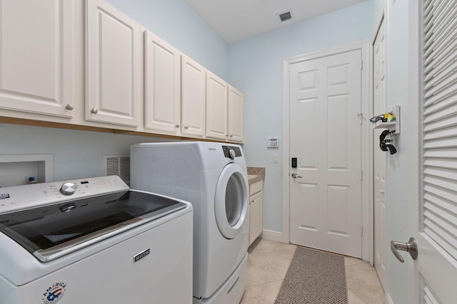 washroom with light tile patterned floors, separate washer and dryer, and cabinets