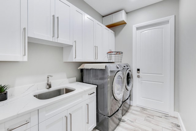 clothes washing area featuring separate washer and dryer, light wood-type flooring, cabinets, and sink