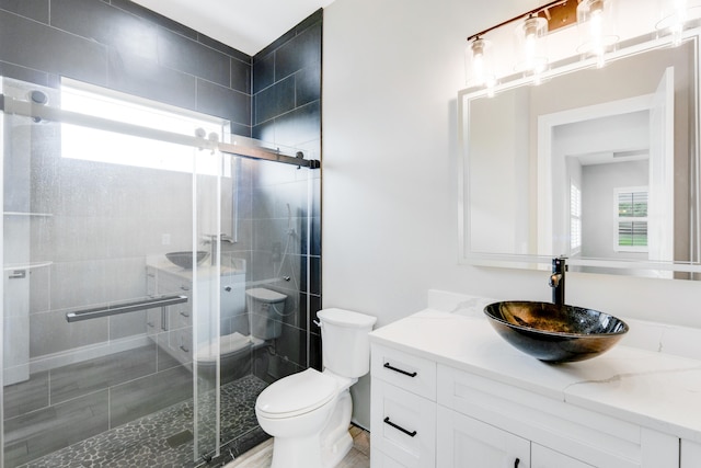 bathroom with a shower with shower door, toilet, and vanity