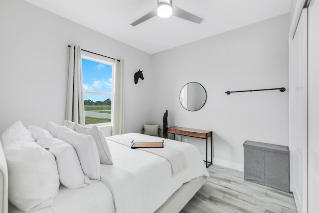 bedroom featuring light hardwood / wood-style flooring, ceiling fan, and a closet