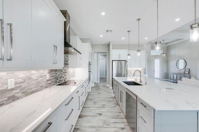 kitchen featuring a large island with sink, sink, decorative light fixtures, and appliances with stainless steel finishes