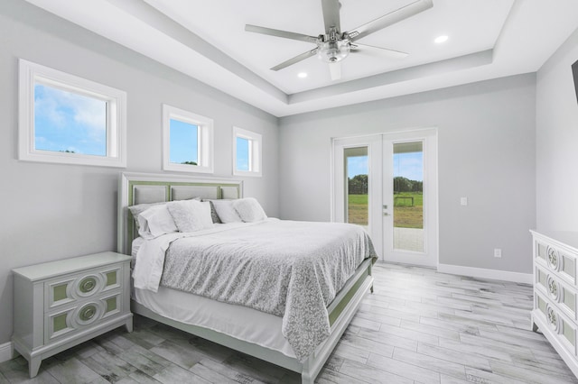 bedroom featuring access to exterior, ceiling fan, a raised ceiling, and light wood-type flooring