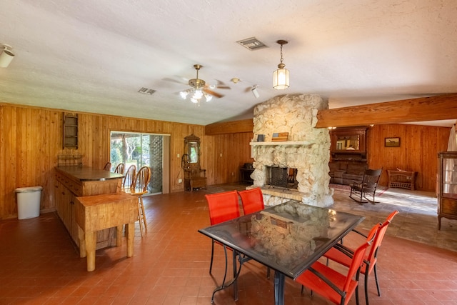 dining room with a fireplace, lofted ceiling, ceiling fan, and wooden walls