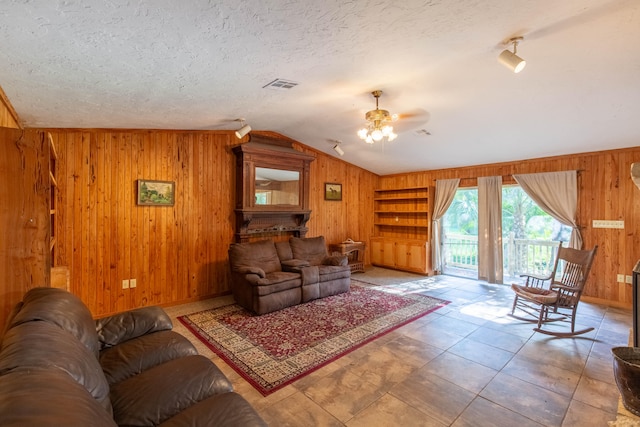 living room featuring built in features, a textured ceiling, wood walls, ceiling fan, and lofted ceiling