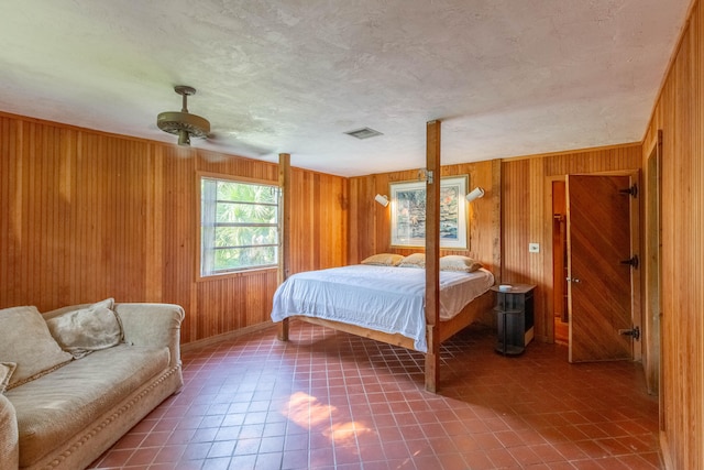 bedroom featuring a textured ceiling, ceiling fan, and wood walls