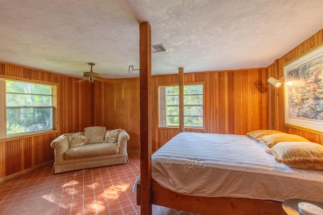 bedroom with a textured ceiling, wooden walls, and tile patterned floors