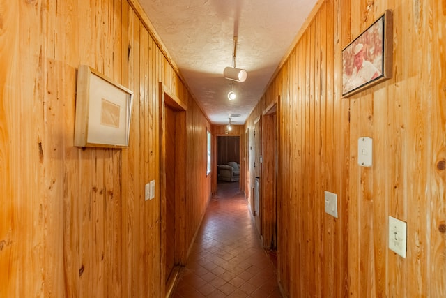 corridor with wooden walls and a textured ceiling