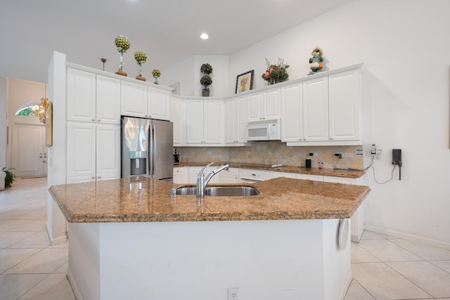 kitchen with white cabinetry, a kitchen island with sink, sink, and stainless steel fridge