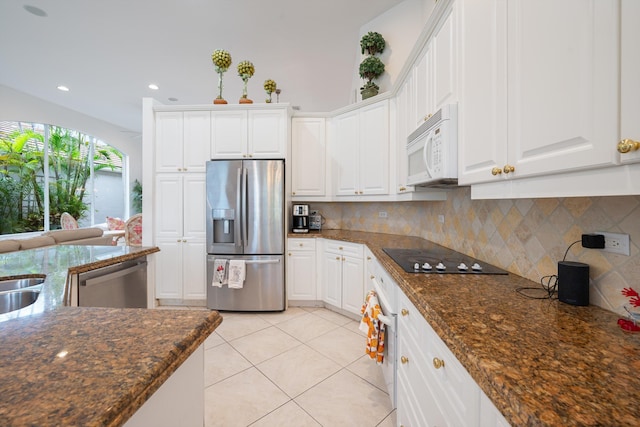 kitchen featuring appliances with stainless steel finishes, dark stone counters, and white cabinets