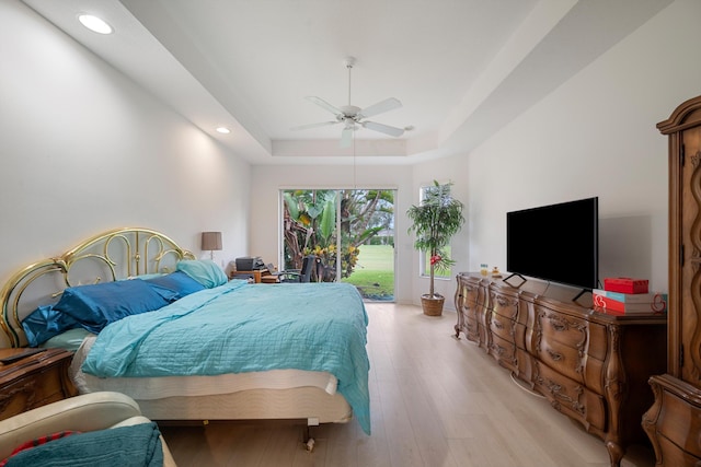 bedroom featuring a tray ceiling, access to exterior, light wood-type flooring, and ceiling fan