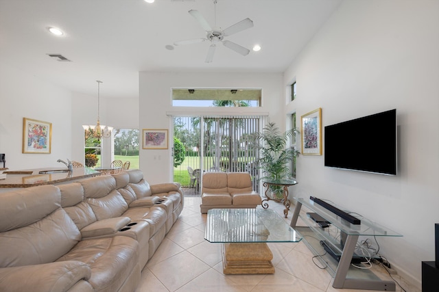 tiled living room with a high ceiling and ceiling fan with notable chandelier