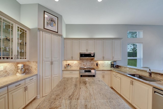 kitchen with light stone counters, stainless steel appliances, tasteful backsplash, and sink