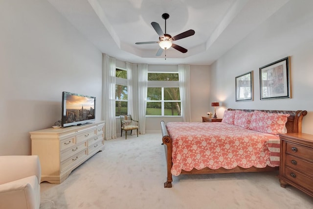 bedroom featuring ceiling fan, light colored carpet, and a raised ceiling