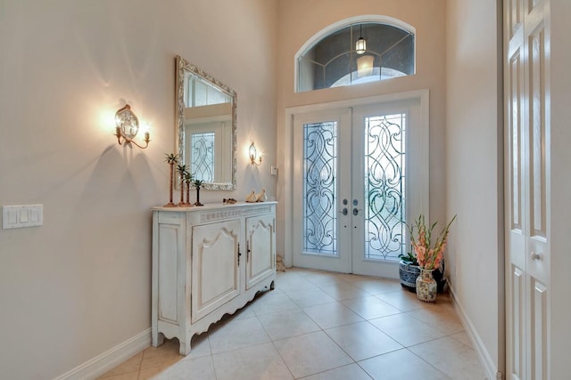 tiled foyer entrance featuring a healthy amount of sunlight, a high ceiling, and french doors