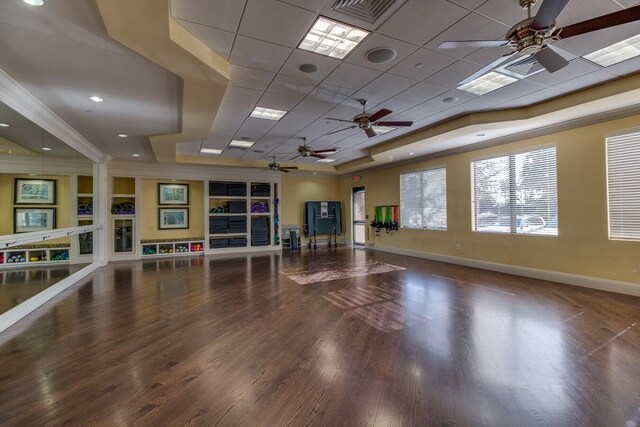 exercise area with a tray ceiling, crown molding, ceiling fan, and dark hardwood / wood-style floors