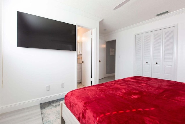 bedroom featuring crown molding, light hardwood / wood-style floors, ceiling fan, connected bathroom, and a textured ceiling