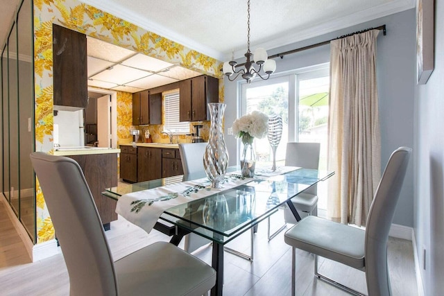 dining space featuring ornamental molding, a chandelier, light hardwood / wood-style flooring, and sink