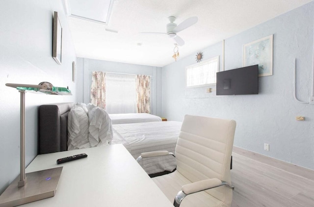 bedroom featuring a textured ceiling, ceiling fan, multiple windows, and light hardwood / wood-style floors