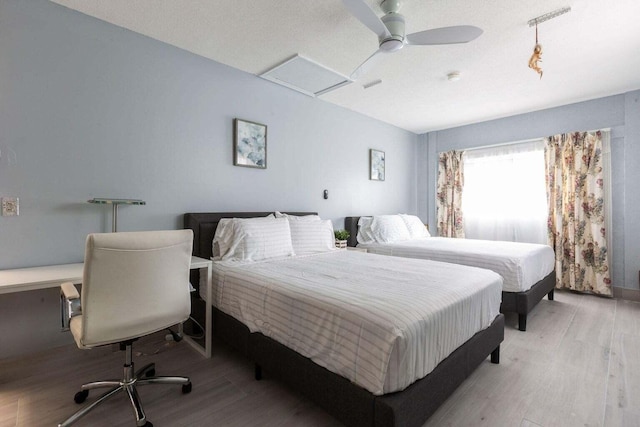 bedroom featuring ceiling fan, light hardwood / wood-style floors, and a textured ceiling