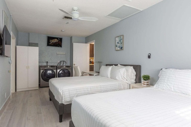 bedroom featuring ceiling fan, separate washer and dryer, and light wood-type flooring