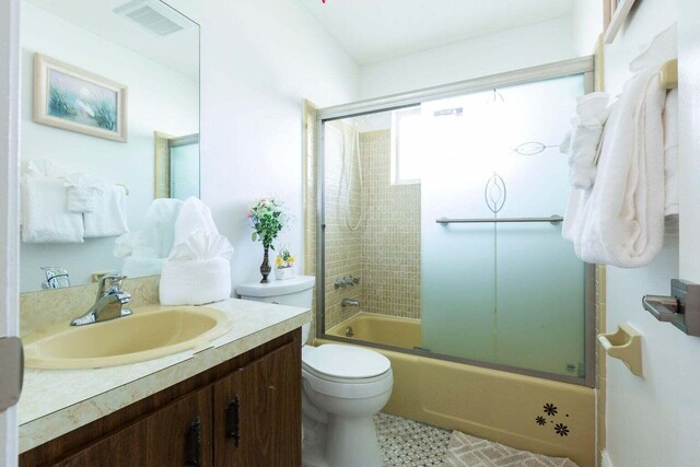 full bathroom with vanity, toilet, bath / shower combo with glass door, and tile patterned floors