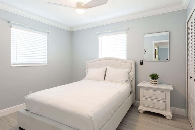 bedroom featuring light wood-type flooring, a closet, ceiling fan, and crown molding