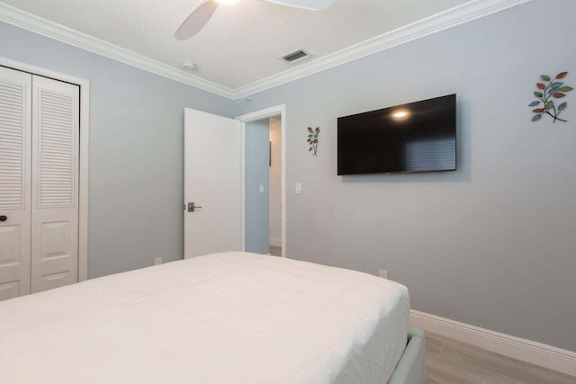 bedroom with a textured ceiling, a closet, hardwood / wood-style floors, crown molding, and ceiling fan