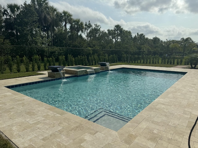 view of swimming pool featuring pool water feature, a patio area, and an in ground hot tub