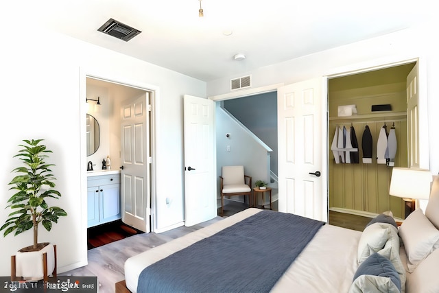 bedroom featuring ensuite bath, wood-type flooring, sink, and a closet