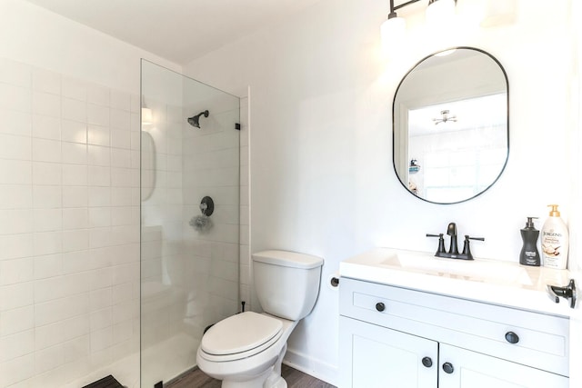 bathroom with vanity, toilet, wood-type flooring, and a tile shower