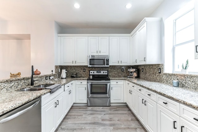 kitchen with white cabinets, appliances with stainless steel finishes, tasteful backsplash, and sink