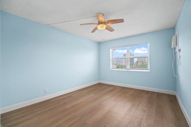 unfurnished room featuring a textured ceiling, ceiling fan, light wood-type flooring, and a wall mounted air conditioner