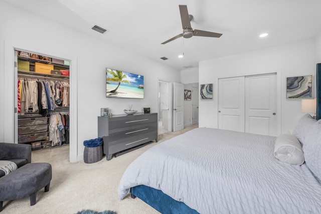 bedroom with ceiling fan, light carpet, and multiple closets