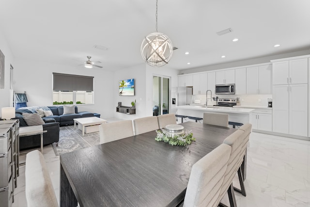 dining space with sink, ceiling fan with notable chandelier, and light tile patterned flooring