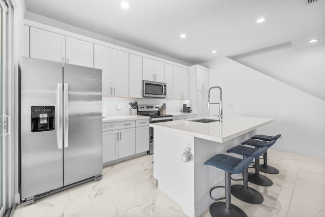 kitchen with white cabinetry, sink, an island with sink, appliances with stainless steel finishes, and light tile patterned flooring