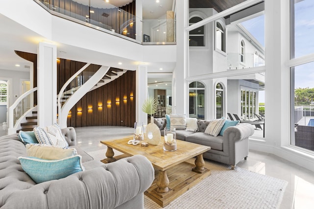 living room with wooden walls, a high ceiling, and stairs