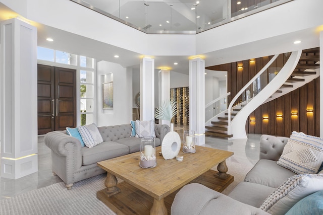 living room featuring ornate columns, stairs, a high ceiling, and recessed lighting