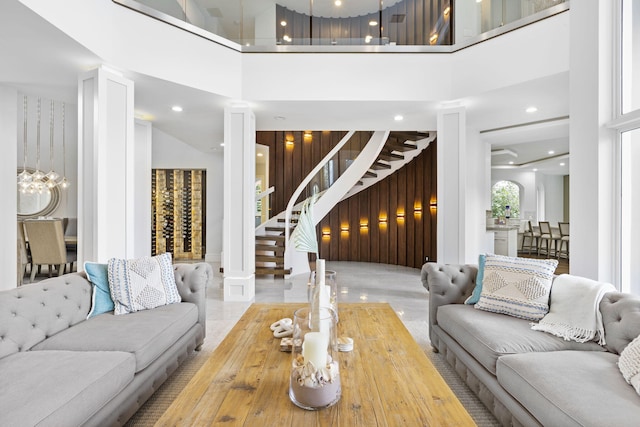 living room featuring wood walls, stairs, a high ceiling, and recessed lighting