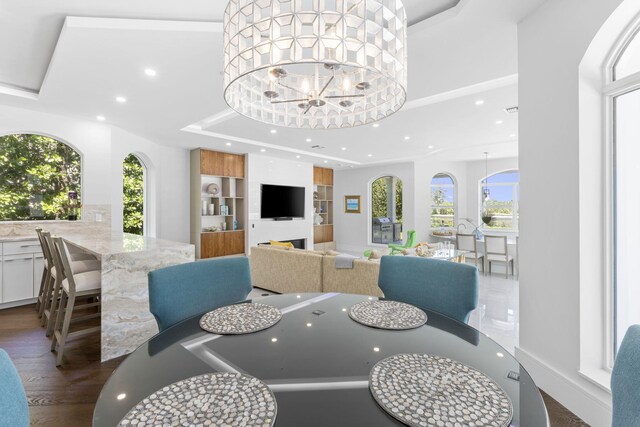 dining room featuring a tray ceiling, dark hardwood / wood-style flooring, a healthy amount of sunlight, and a chandelier